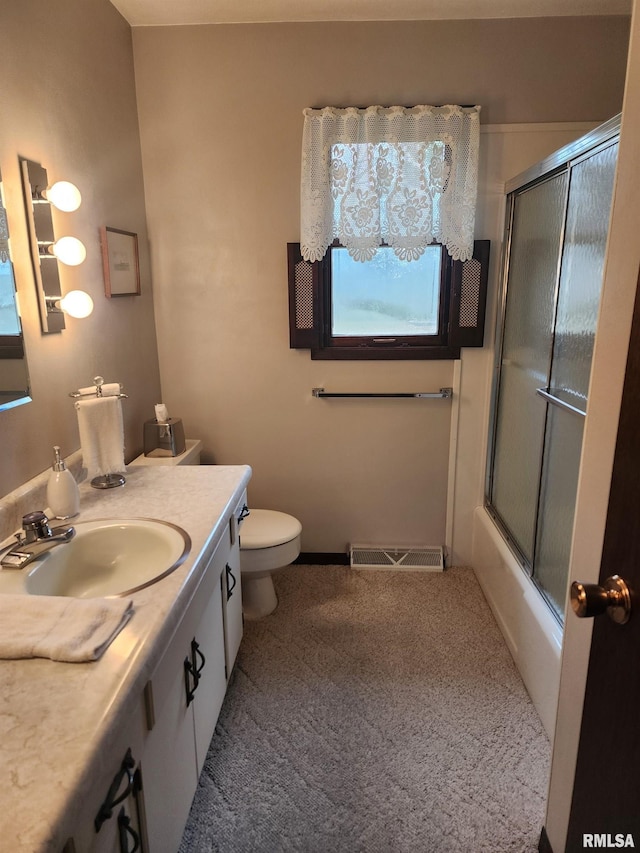 full bathroom featuring vanity, combined bath / shower with glass door, and toilet