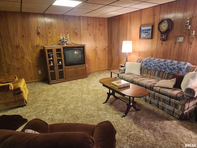 living room featuring a drop ceiling, wood walls, and light carpet