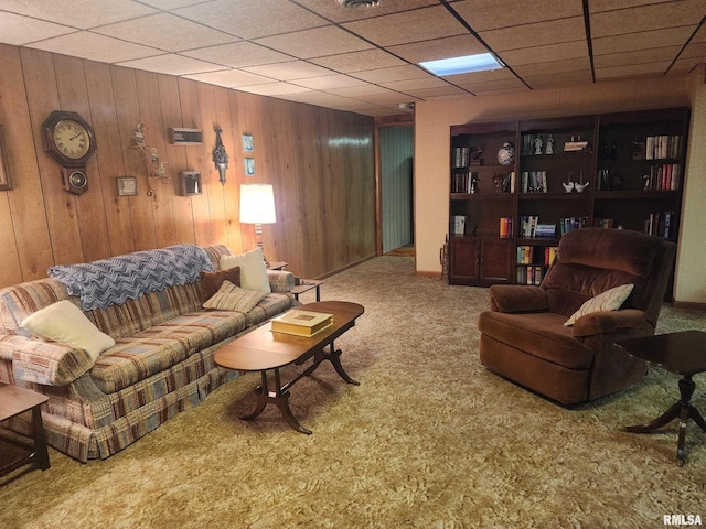 carpeted living room with a drop ceiling and wooden walls