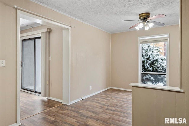 unfurnished room featuring ceiling fan, wood-type flooring, ornamental molding, and a textured ceiling