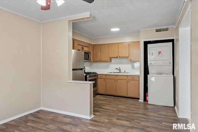 kitchen featuring appliances with stainless steel finishes, stacked washer and clothes dryer, sink, and dark wood-type flooring