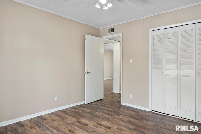 unfurnished bedroom featuring ceiling fan, dark hardwood / wood-style floors, ornamental molding, a textured ceiling, and a closet