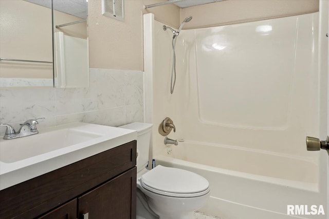 full bathroom with vanity, toilet, tub / shower combination, and tile walls