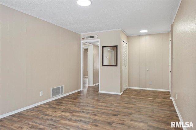 spare room featuring ornamental molding, dark hardwood / wood-style floors, and a textured ceiling