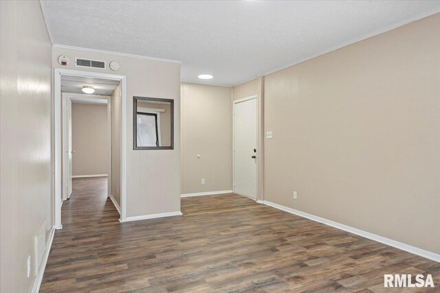 empty room featuring ornamental molding, dark wood-type flooring, and a textured ceiling