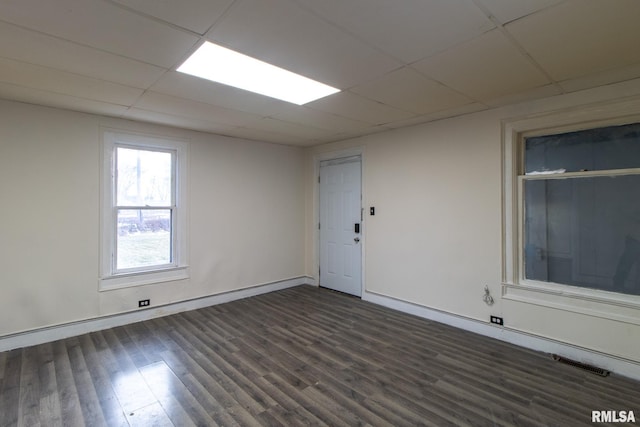 spare room with dark wood-style floors, a paneled ceiling, visible vents, and baseboards