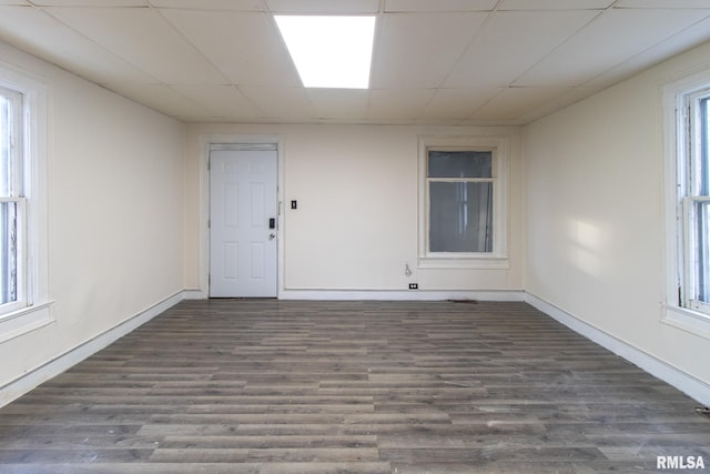 unfurnished room with a paneled ceiling, a healthy amount of sunlight, and wood finished floors