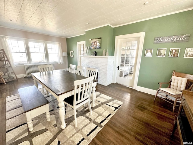 dining space with radiator, a fireplace, dark wood-type flooring, and ornamental molding