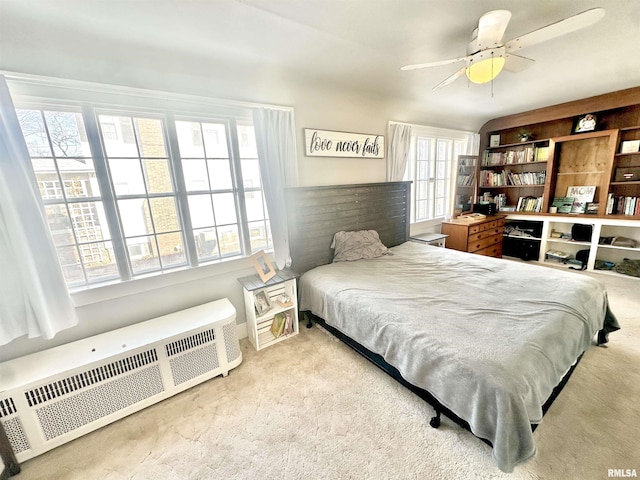 bedroom featuring radiator heating unit, light colored carpet, and ceiling fan