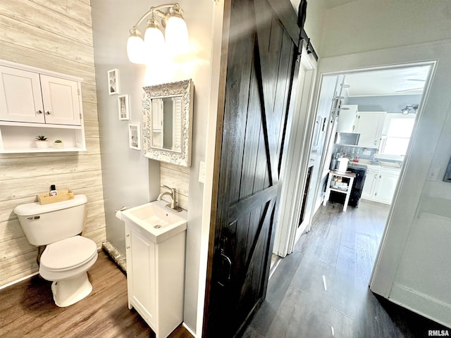 bathroom with vanity, hardwood / wood-style flooring, toilet, and wood walls