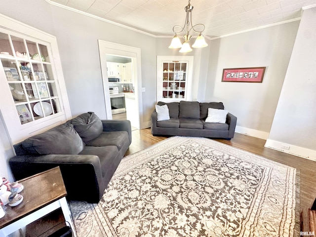 living room with wood-type flooring, ornamental molding, and a notable chandelier