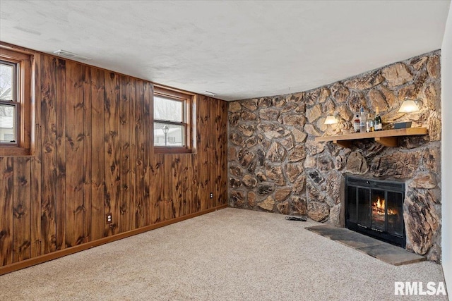 unfurnished living room featuring wood walls, a fireplace, and light carpet