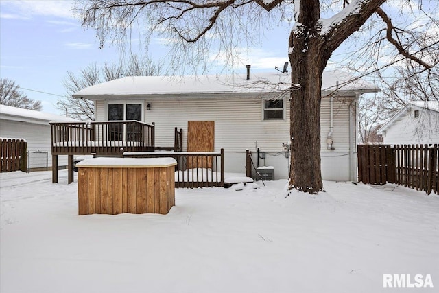 snow covered back of property featuring a deck