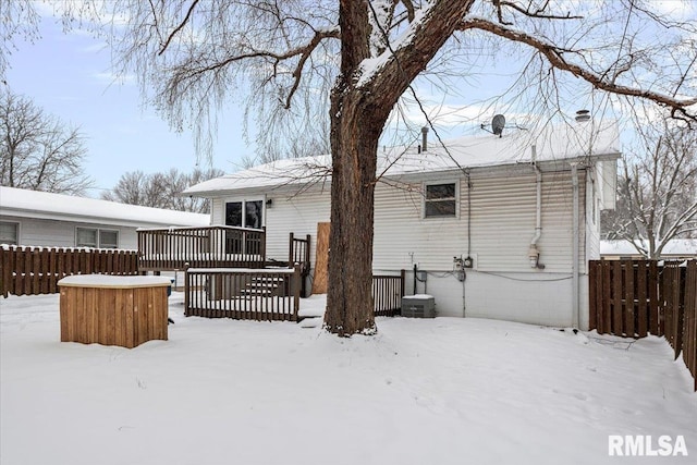 snow covered house with a wooden deck