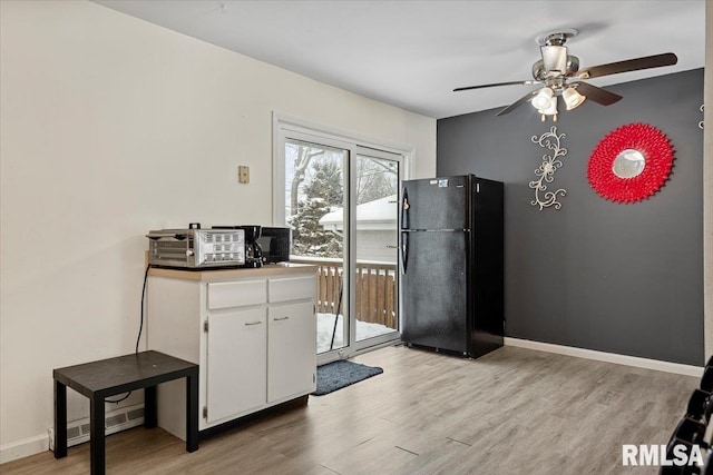 kitchen featuring ceiling fan, black refrigerator, white cabinets, and light hardwood / wood-style floors