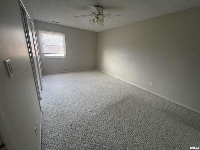 empty room with a textured ceiling, light colored carpet, and ceiling fan