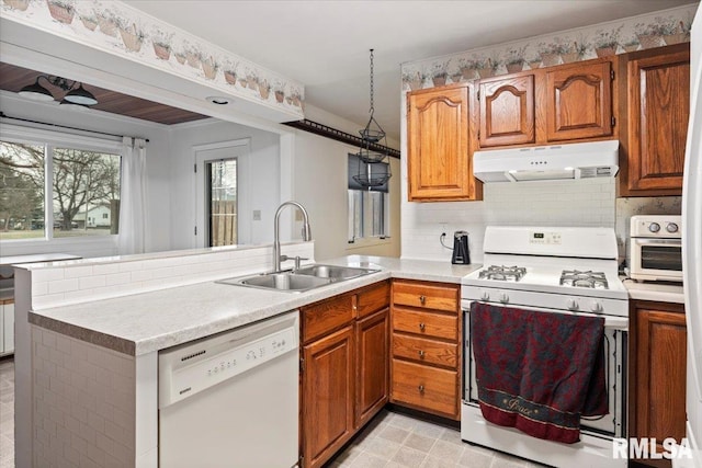 kitchen featuring sink, white appliances, backsplash, and kitchen peninsula