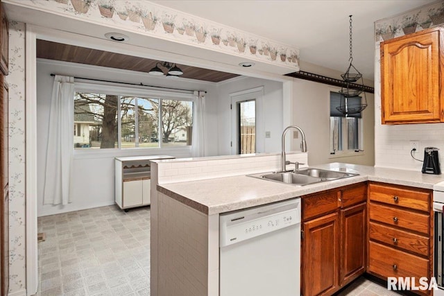 kitchen with kitchen peninsula, backsplash, decorative light fixtures, dishwasher, and sink