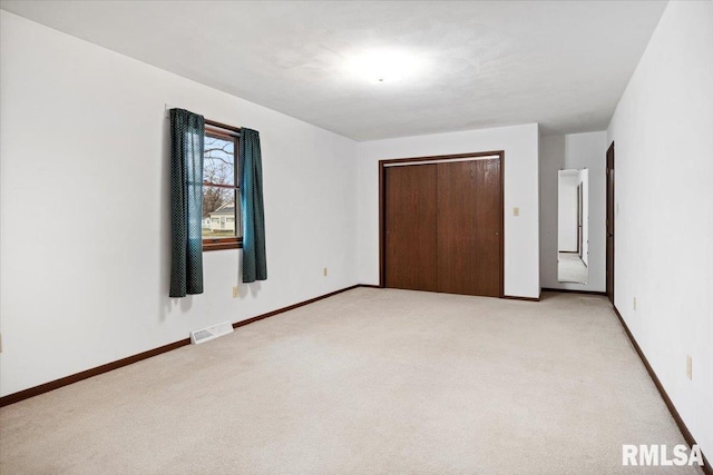 unfurnished bedroom with light colored carpet and a closet