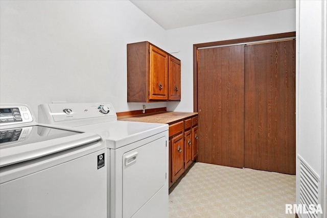 clothes washing area featuring separate washer and dryer and cabinets