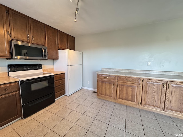 kitchen featuring electric stove, light tile patterned floors, white fridge, and rail lighting