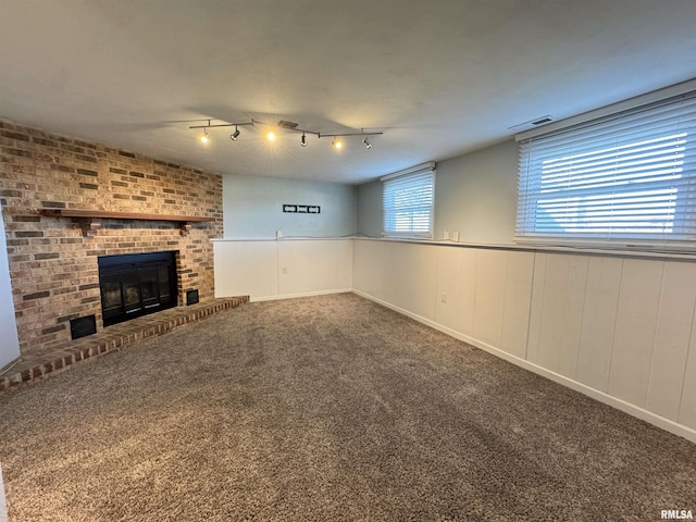 unfurnished living room featuring carpet floors, rail lighting, and a fireplace