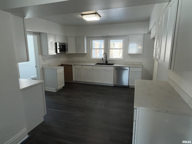 kitchen with dark wood-style floors, stainless steel appliances, a sink, and white cabinetry