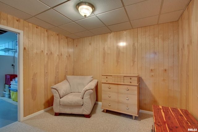 sitting room featuring carpet flooring and wood walls