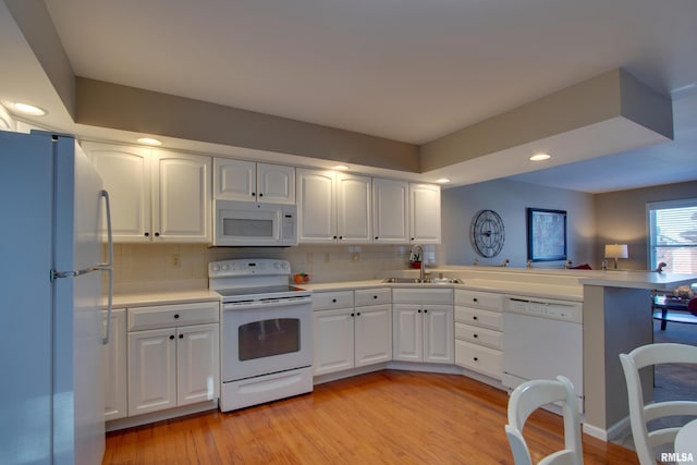 kitchen featuring white appliances, white cabinets, sink, tasteful backsplash, and light hardwood / wood-style floors