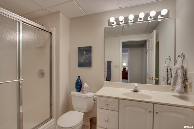 bathroom with a paneled ceiling, vanity, toilet, and walk in shower