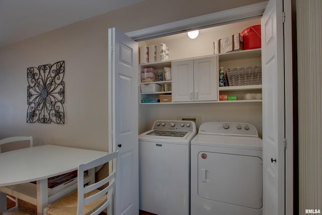 clothes washing area with separate washer and dryer and cabinets