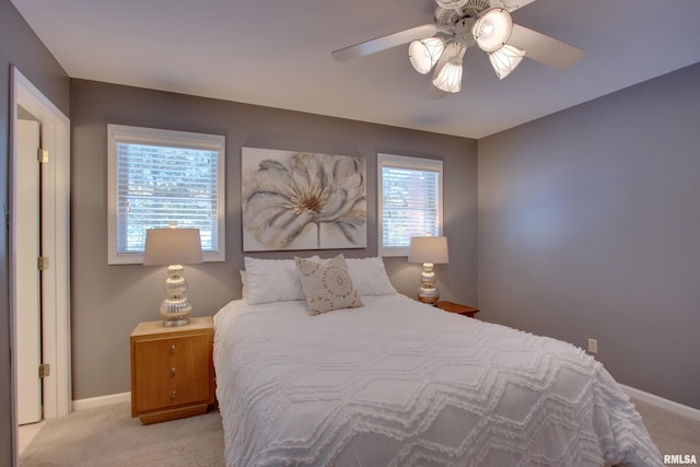 bedroom with ceiling fan, light colored carpet, and multiple windows