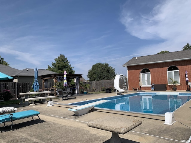 view of swimming pool with a fenced in pool, a fenced backyard, a water slide, a patio area, and a diving board