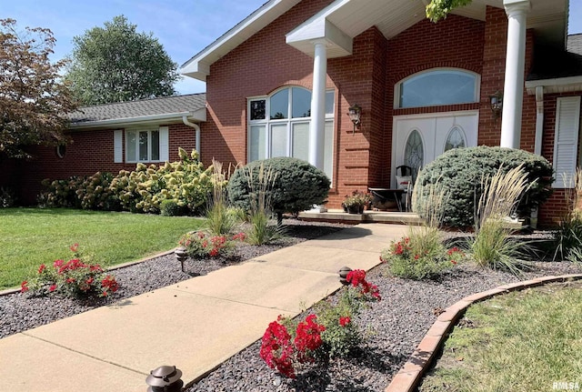 property entrance with brick siding and a lawn