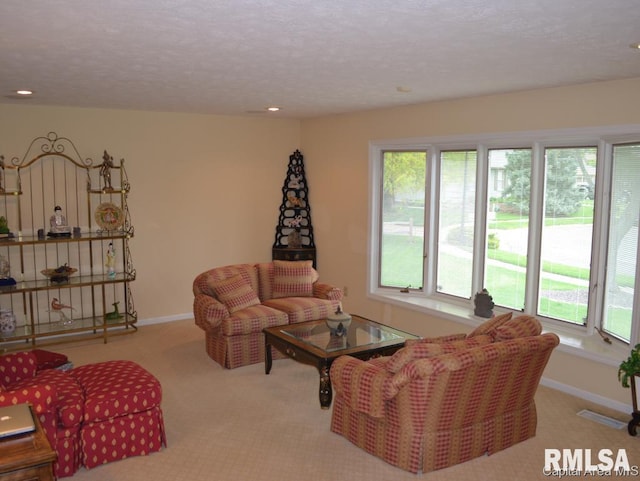 carpeted living area featuring baseboards, a textured ceiling, and recessed lighting