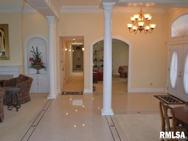 entryway featuring crown molding, a high ceiling, baseboards, decorative columns, and an inviting chandelier