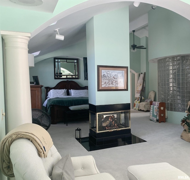 carpeted bedroom with vaulted ceiling and a multi sided fireplace