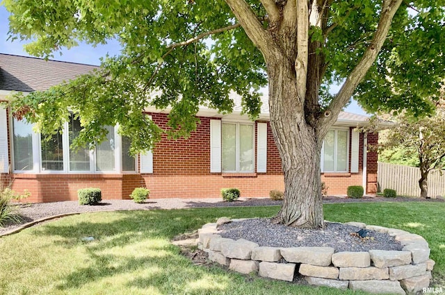 exterior space with a yard, brick siding, and fence