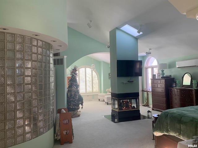 carpeted bedroom with a skylight, visible vents, arched walkways, an AC wall unit, and a multi sided fireplace