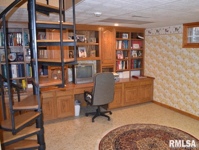 office area featuring wallpapered walls, baseboards, and built in desk