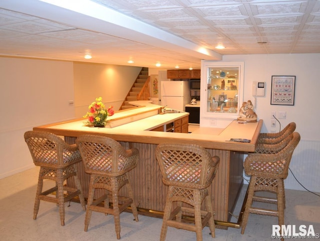 bar with stairway, freestanding refrigerator, light carpet, a bar, and black microwave