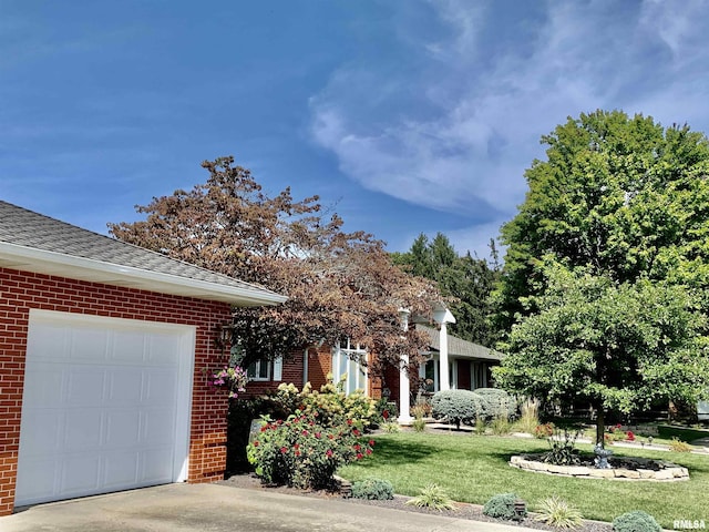 view of front of home with concrete driveway, roof with shingles, an attached garage, a front lawn, and brick siding