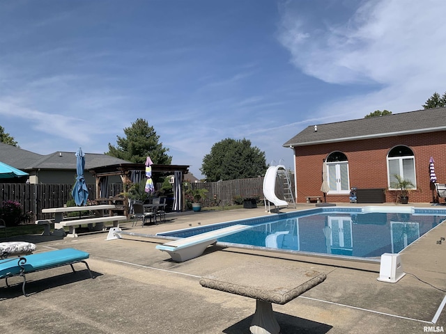 view of swimming pool with a fenced in pool, a patio, a fenced backyard, a water slide, and a diving board