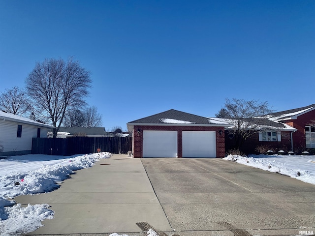 exterior space featuring a garage, driveway, brick siding, and fence