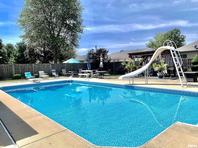 view of swimming pool with a fenced in pool, a water slide, fence, and a patio