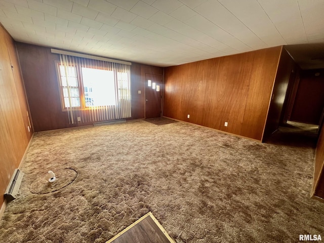 carpeted spare room with baseboard heating and wooden walls