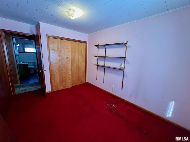 unfurnished bedroom featuring crown molding, a closet, and dark colored carpet