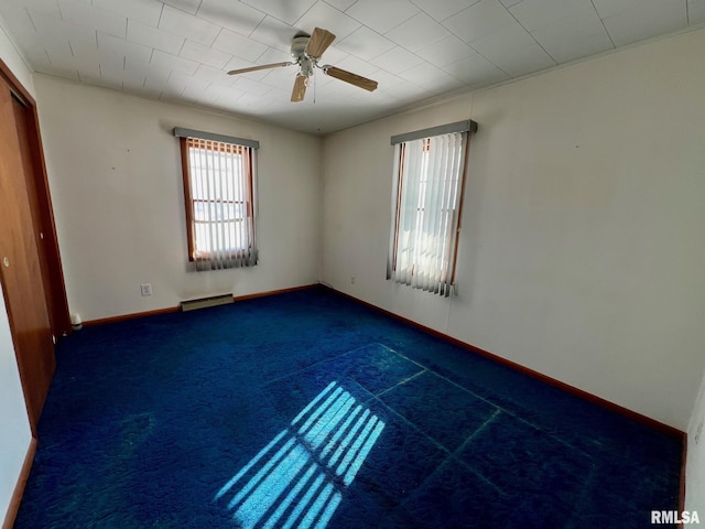 unfurnished room featuring ceiling fan, baseboard heating, plenty of natural light, and dark carpet