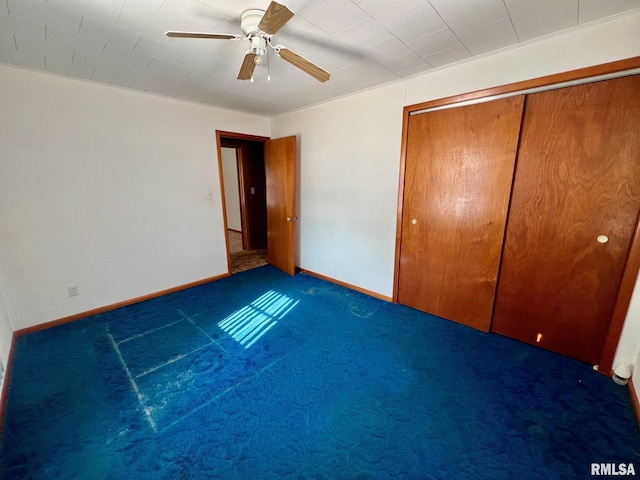 unfurnished bedroom featuring ceiling fan, a closet, and dark carpet