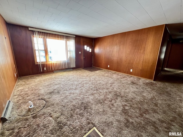 unfurnished living room with wooden walls, carpet floors, and a baseboard heating unit